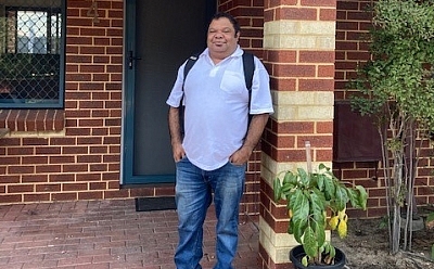 A man standing in front of a brick house