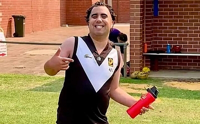 Aaron with a water bottle standing on the grass wearing a football uniform