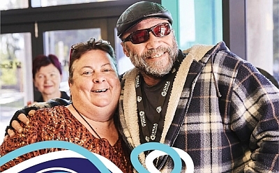 Teo people with their arms wrapped around each other with big smiles on their faces. Overlayed on the photo is a St Bart's graphic that says: