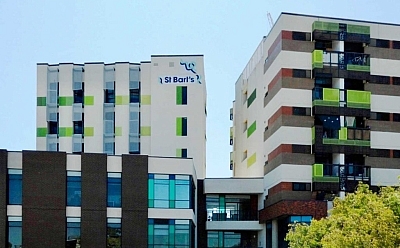 Tall multi-story St Bart's buildings with bright green squares of paint decorating them.